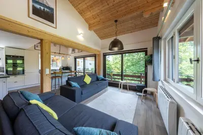 a living room with a blue couch and a kitchen at Le Bord Du Nant in Arâches-la-Frasse
