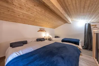 two beds in a room with wooden ceilings at Le Bord Du Nant in Arâches-la-Frasse