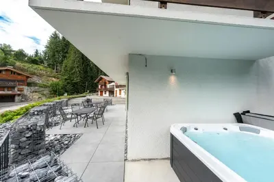 a hot tub on the balcony of a house at Le Bord Du Nant in Arâches-la-Frasse