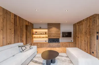 a living room with wooden walls and a couch and a table at Le Refuge contemporain - Welkeys in Megève