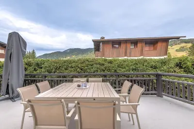 a wooden table and chairs on a balcony at Le Refuge contemporain - Welkeys in Megève