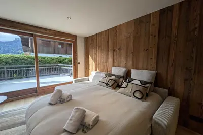 a bedroom with a large bed and a large window at Le Refuge contemporain - Welkeys in Megève