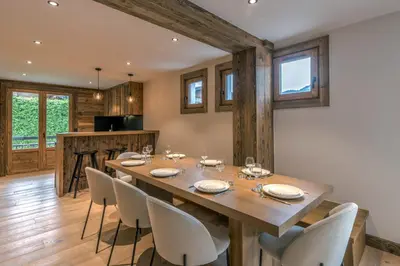 a dining room with a wooden table and chairs at Le Refuge contemporain - Welkeys in Megève