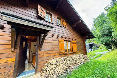 a wooden house with a pile of fire wood next to it at Chalet facing Mont Blanc calm and comfort in Saint-Gervais-les-Bains
