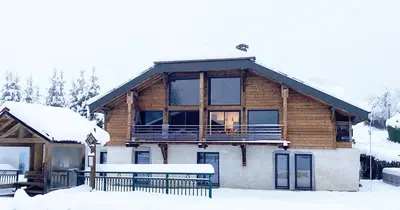 a log cabin in the snow with benches in front at Du Côté de Chez Sou in Arâches-la-Frasse