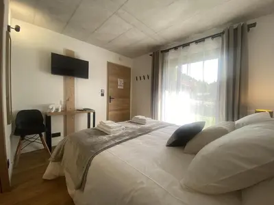 a bedroom with a large white bed with a window at Du Côté de Chez Sou in Arâches-la-Frasse