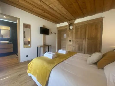a bedroom with a large bed with a clock on the wall at Du Côté de Chez Sou in Arâches-la-Frasse
