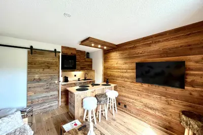 a kitchen with wooden walls and a bar with stools at Apartment Les Cimes Blanches in Combloux