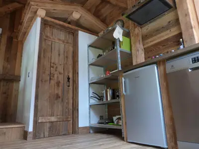 a kitchen with a refrigerator and a wooden door at La Cubelette in Chamonix-Mont-Blanc