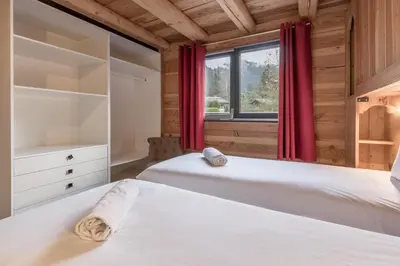 two beds in a bedroom with a window at Le Grand Champs - Chalet prive avec terrasse et vue in Chamonix-Mont-Blanc