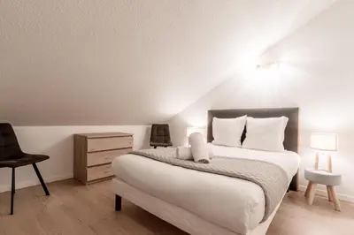 a bedroom with a large bed and a chair at Duplex - Aiguille du Midi - Centre in Chamonix-Mont-Blanc