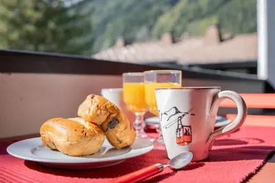 a table with a plate of bread and a cup of orange juice at Appartement T4 familial à Chamonix, avec Parking et près des Grand Montets in Chamonix-Mont-Blanc