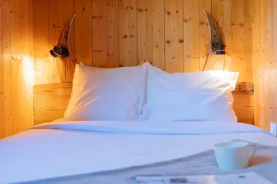 a bedroom with a bed with white pillows and a wooden wall at Appartement T4 familial à Chamonix, avec Parking et près des Grand Montets in Chamonix-Mont-Blanc