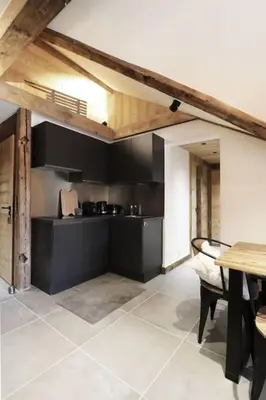 a kitchen with black walls and a table and a table and chairs at Logement de vacances exclusif - Plein centre in Arâches-la-Frasse
