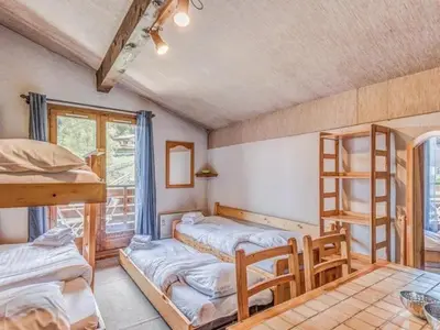 a room with three bunk beds and a table at Bel appartement au pied des pistes-Megeve in Demi-Quartier
