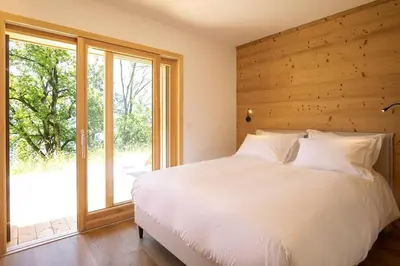 a bedroom with a white bed and a large window at L'Ecrin in Plateau dʼAssy