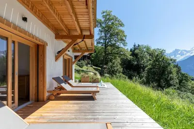 a wooden deck with chairs on a house at L'Ecrin in Plateau dʼAssy