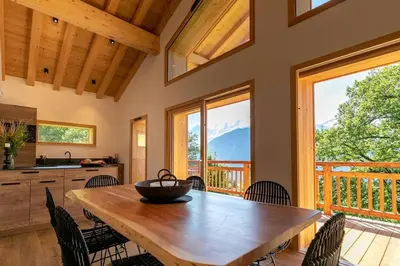 a kitchen and dining room with a wooden table and chairs at L'Ecrin in Plateau dʼAssy