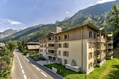 a building on the side of a road next to a mountain at White Pearl - Centre de Chamonix - 2ch - Renove in Chamonix-Mont-Blanc