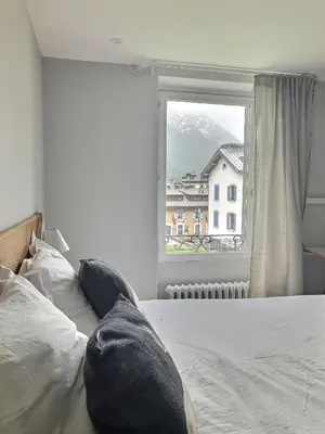 a bedroom with a bed with a large window at Magnifique Appartement au Centre de Chamonix in Chamonix-Mont-Blanc