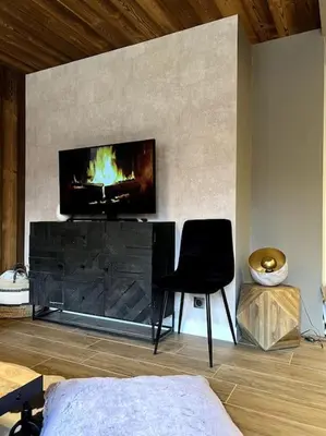 a room with a fireplace with a chair and a television at Megève appartement centre ville palais des sports in Megève