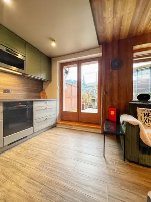a kitchen with a table and a red laptop on a chair at Megève appartement centre ville palais des sports in Megève