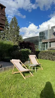 two chairs sitting in the grass near a building at Megève appartement centre ville palais des sports in Megève