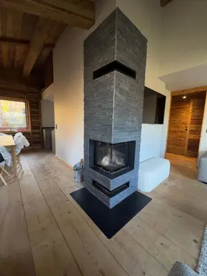 a living room with a stone fireplace in a house at Duplex aux pieds des pistes à Rochebrune in Megève