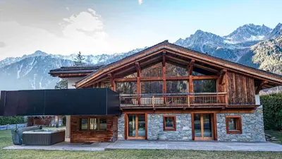 a log house with mountains in the background at Chalet Bonami 450 m2 salle cinema jacuzzi hammam in Chamonix-Mont-Blanc
