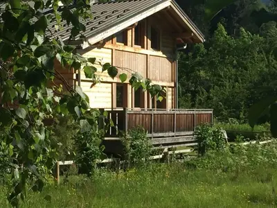 a wooden cabin with a porch in a field at Demi Chalet au coeur de Chamonix - Zefi in Chamonix-Mont-Blanc