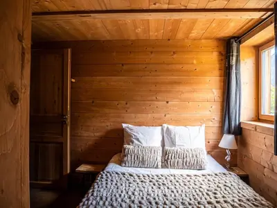 a bedroom with a bed with a wooden wall at Demi Chalet au coeur de Chamonix - Zefi in Chamonix-Mont-Blanc