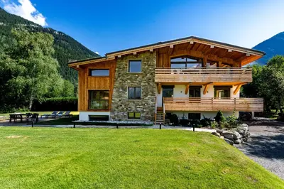 a house in the mountains with a green lawn at Chalet Josephine, Chamonix Les Bois in Chamonix-Mont-Blanc