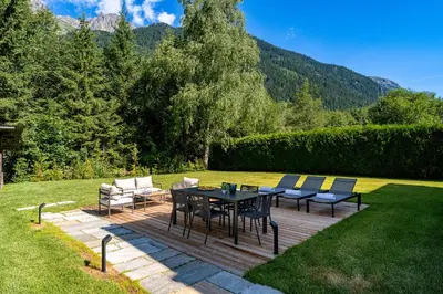a patio with a table and chairs in a yard at Chalet Josephine, Chamonix Les Bois in Chamonix-Mont-Blanc