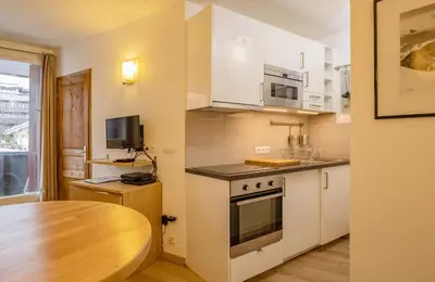 a kitchen with white cabinets and a wooden table at Apartment Lognan 1 - A Chamonix Mont Blanc Haven in Chamonix-Mont-Blanc