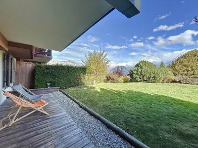 a wooden deck with a chair on a lawn at Confortable 2 pièces avec jardin, parking, face au Mont Blanc - FR-1-560-152 in Combloux