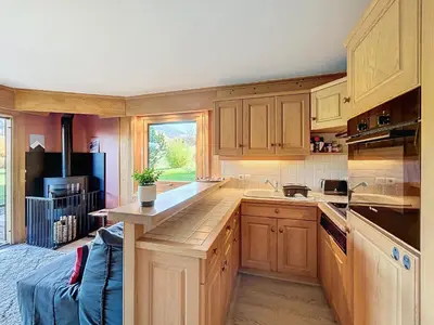 a kitchen with wooden cabinets and a counter top at Confortable 2 pièces avec jardin, parking, face au Mont Blanc - FR-1-560-152 in Combloux