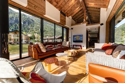 a living room with couches and chairs and large windows at Chalet Cotes du Lavancher in Chamonix-Mont-Blanc
