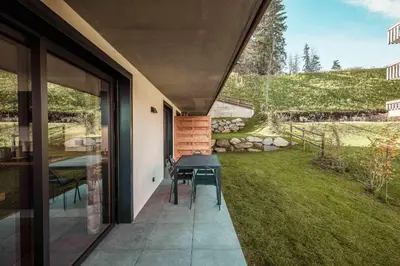 a patio with a table and chairs next to a yard at Apartment Nid des Neiges - Perfect for families in Combloux