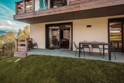 a patio with a table and chairs in front of a house at Apartment Nid des Neiges - Perfect for families in Combloux