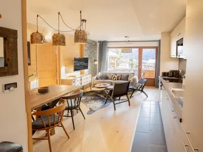 a kitchen and living room with a table and chairs at Bel appartement T3 en résidence neuve avec parking et WIFI, proche du village et ski-bus - FR-1-624-168 in Samoëns