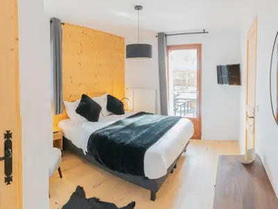 a bedroom with a large bed with a wooden headboard at Bel appartement T3 en résidence neuve avec parking et WIFI, proche du village et ski-bus - FR-1-624-168 in Samoëns