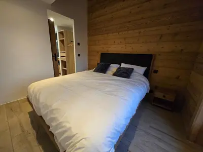 a bedroom with a large white bed with wooden walls at Le chalet des belges - Saint-Gervais in Saint-Gervais-les-Bains