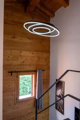a circular light fixture hanging from the ceiling in a room with wood at Premium 200sqm Chalet in Chamonix Valley ! in Chamonix-Mont-Blanc