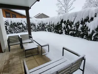 a covered patio with benches and a wall covered in snow at Zorta - Ground floor apartment with private garden in Samoëns