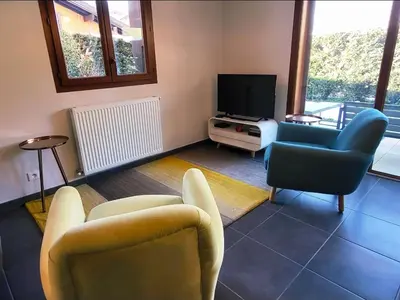a living room with two chairs and a television at Zorta - Ground floor apartment with private garden in Samoëns