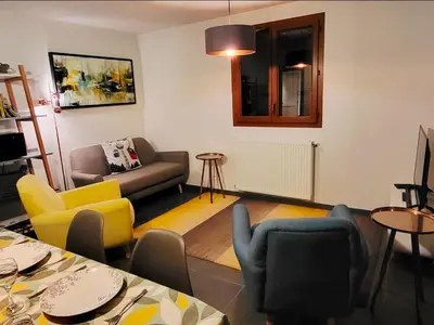 a living room with yellow and blue chairs and a table at Zorta - Ground floor apartment with private garden in Samoëns