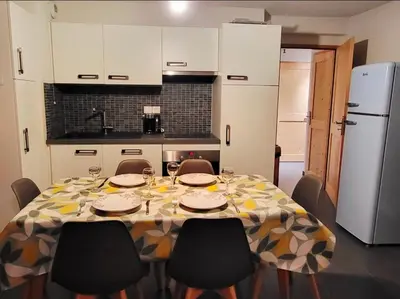 a kitchen with a table with chairs and a kitchen with white cabinets at Zorta - Ground floor apartment with private garden in Samoëns