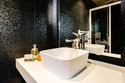 a bathroom with a white sink and a black wall at Chalet lux et Design Chamonix in Servoz