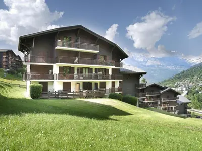 a large building on top of a grassy hill at Studio La Piste-5 by Interhome in Saint-Gervais-les-Bains
