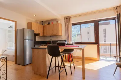 a kitchen with a refrigerator and a table with chairs at Appartement lumineux à Chamonix avec vue imprenable sur Mont Blanc et parking in Chamonix-Mont-Blanc